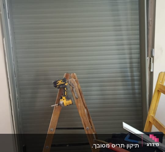 סולם וכלים ליד תריס מותקן